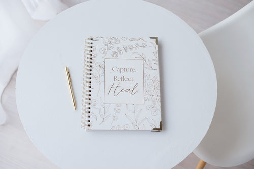 Christian grief journal for pregnancy loss and miscarriage on a white table with a gold pen